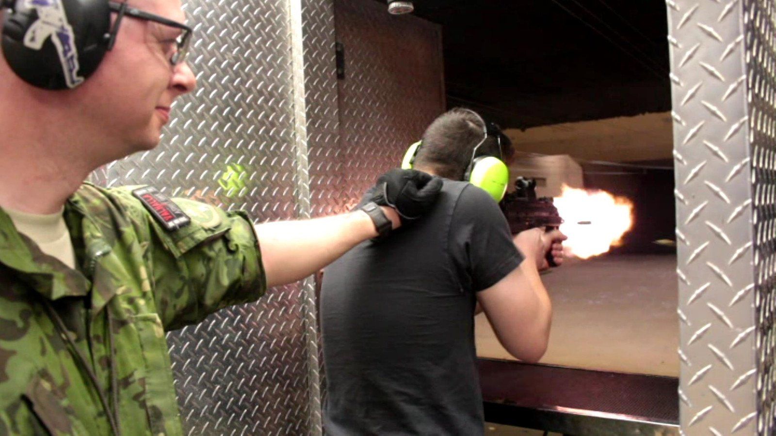 A guest firing a pistol at Battlefield Vegas with a range safety officer beside him